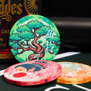 Three colorful poker chips with artistic designs on a dark surface